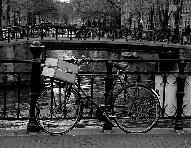 Black-and-white photograph of a bicycle beside an Amsterdam canal